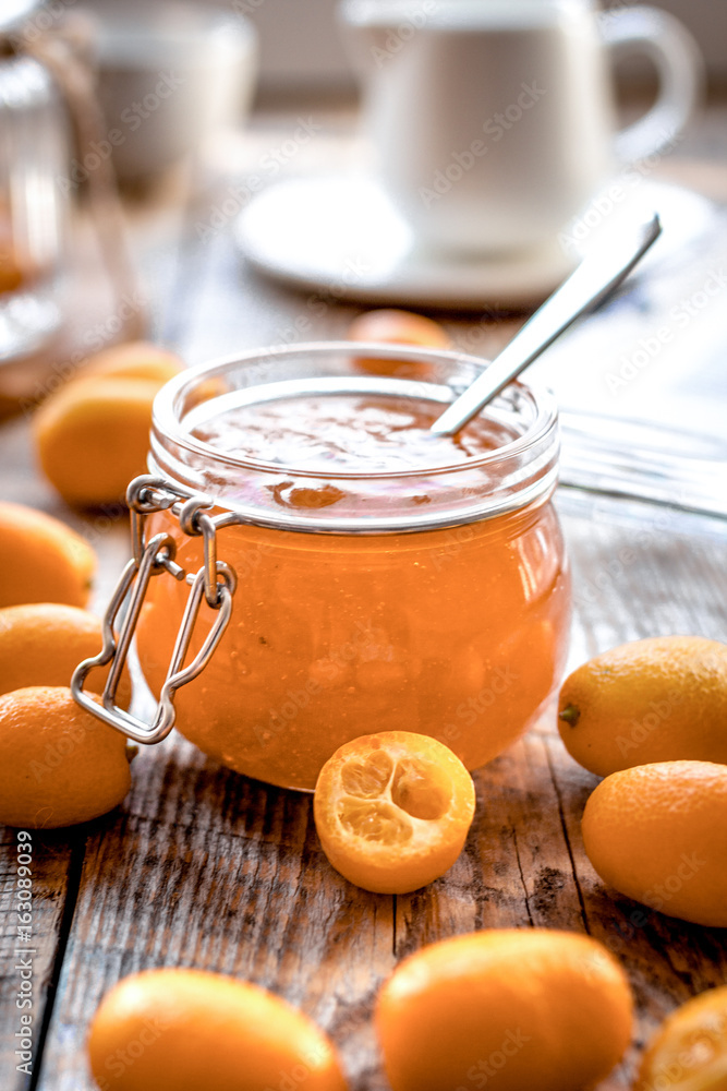 kumquat on plate and jam in jar at wooden table