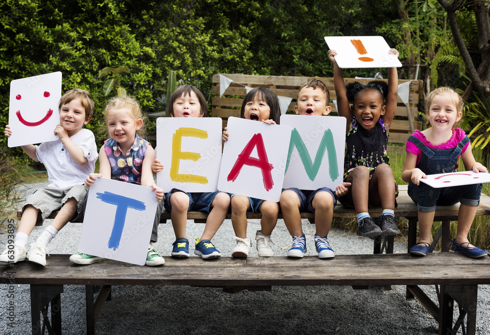 Children are sitting on the wooden table holding a word team