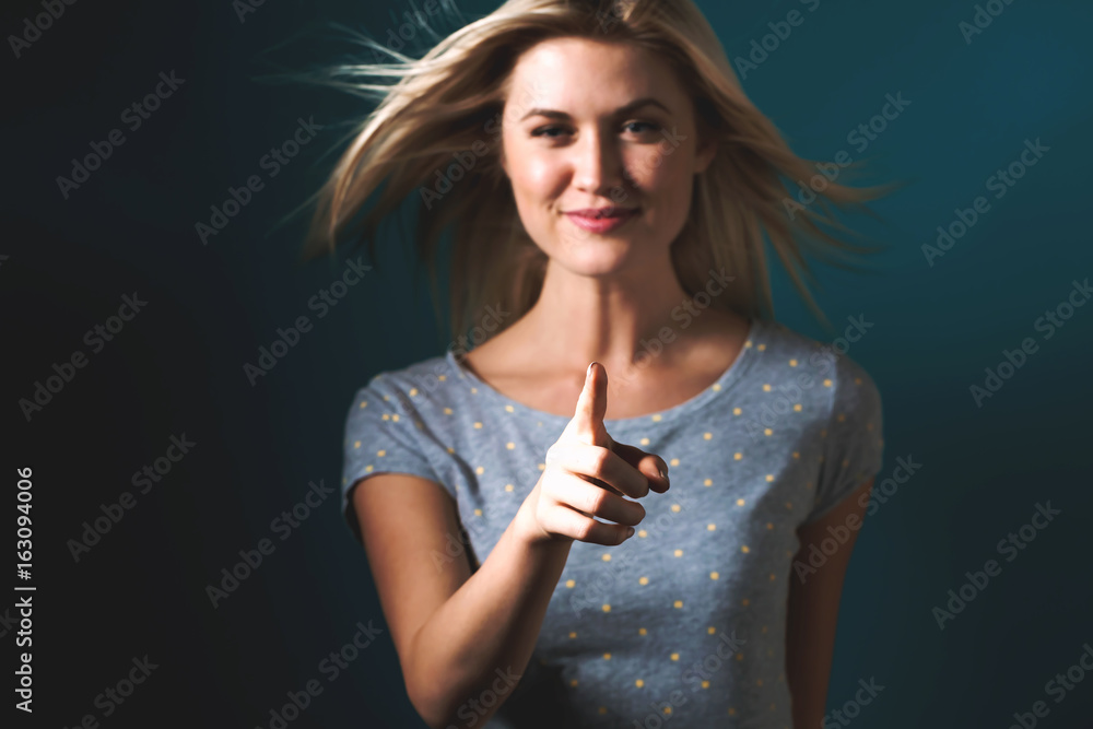 Young woman pointing something on a blue background