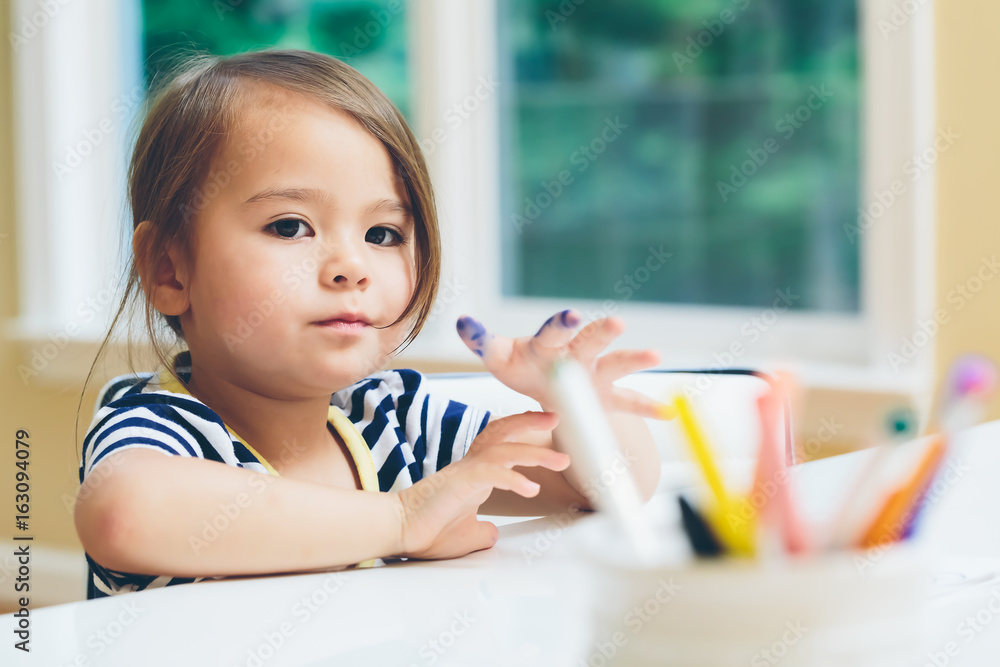 Toddler girl drawing and doing crafts in her house