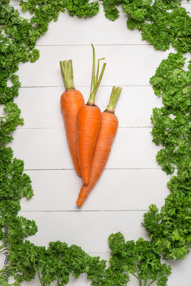 Fresh raw carrots with vegetables on wooden table.