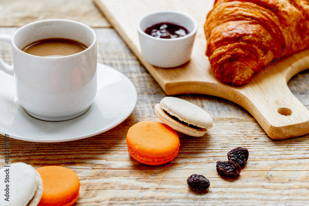 sweet breakfast with coffee, macaroons and croissants on wooden 