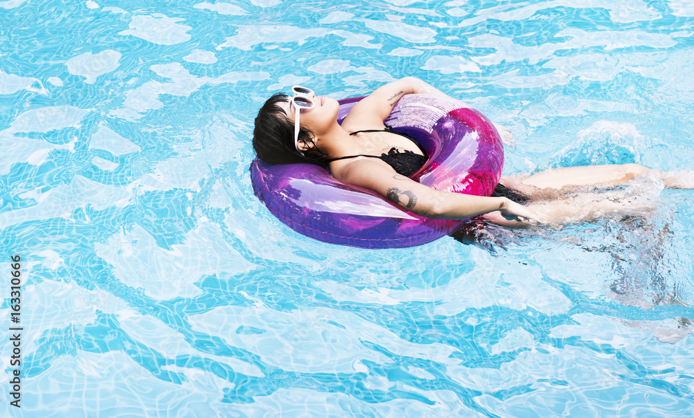 Asian woman floating in the swimming pool with inflatable tube