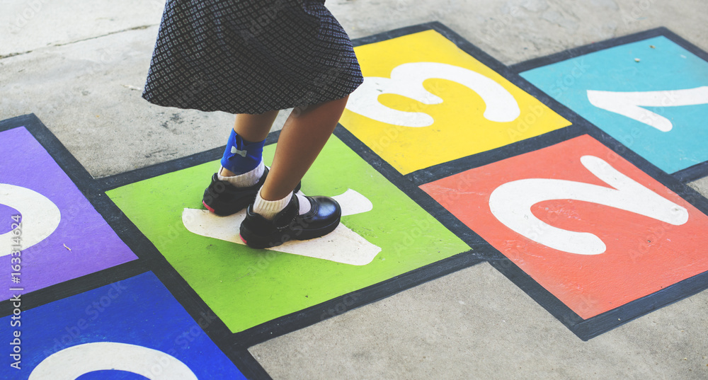 Young girl playing hopscotch