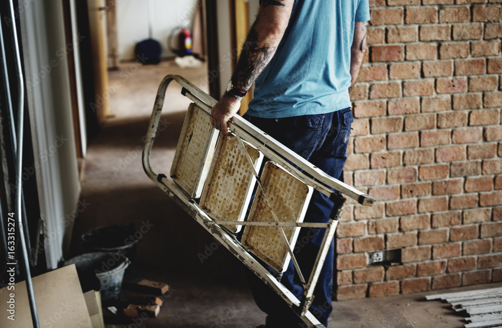 Handyman with tattoo carrying a ladder