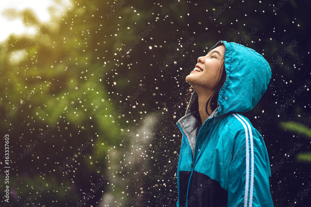 Asian woman wearing a raincoat outdoors. She is happy.