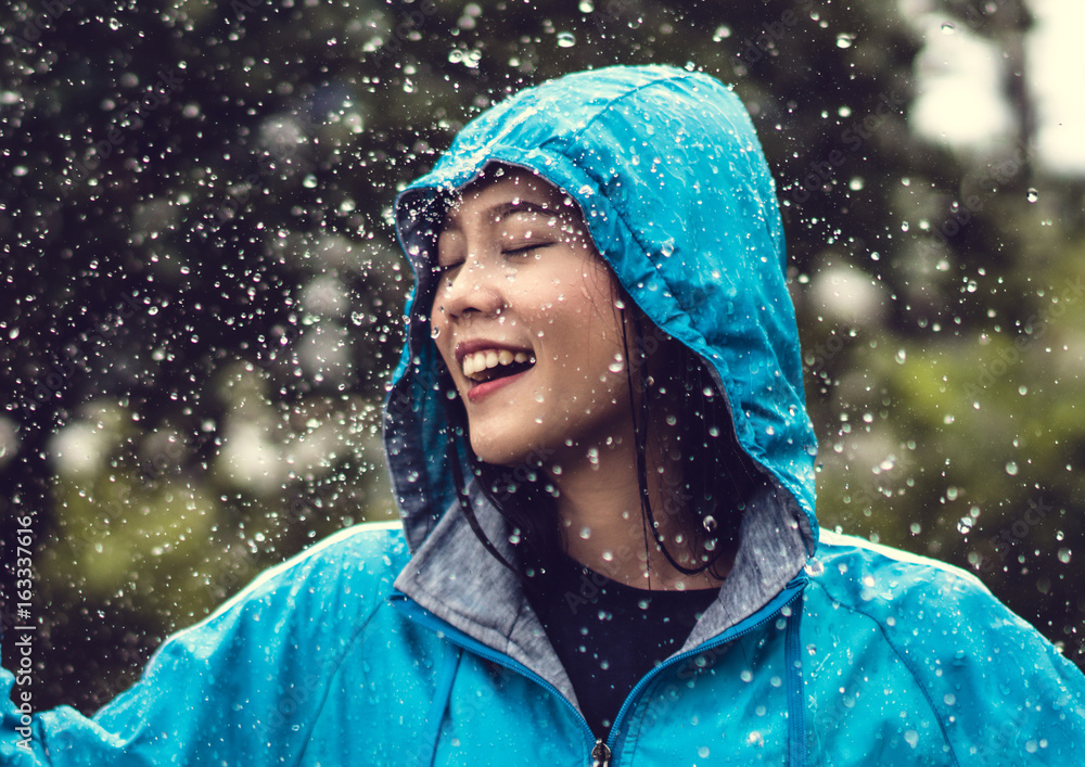 在户外穿着雨衣的亚洲女人。她很开心。