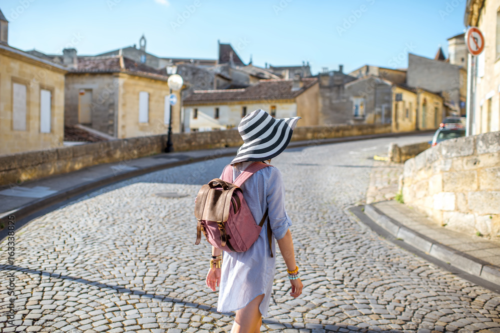 Young woman tourist walking old street at the famous Saint Emilion village in Bordeaux region in Fra