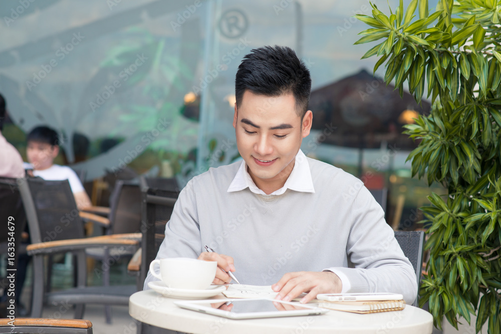 Happy young man working on laptop computer during coffee break in cafe bar