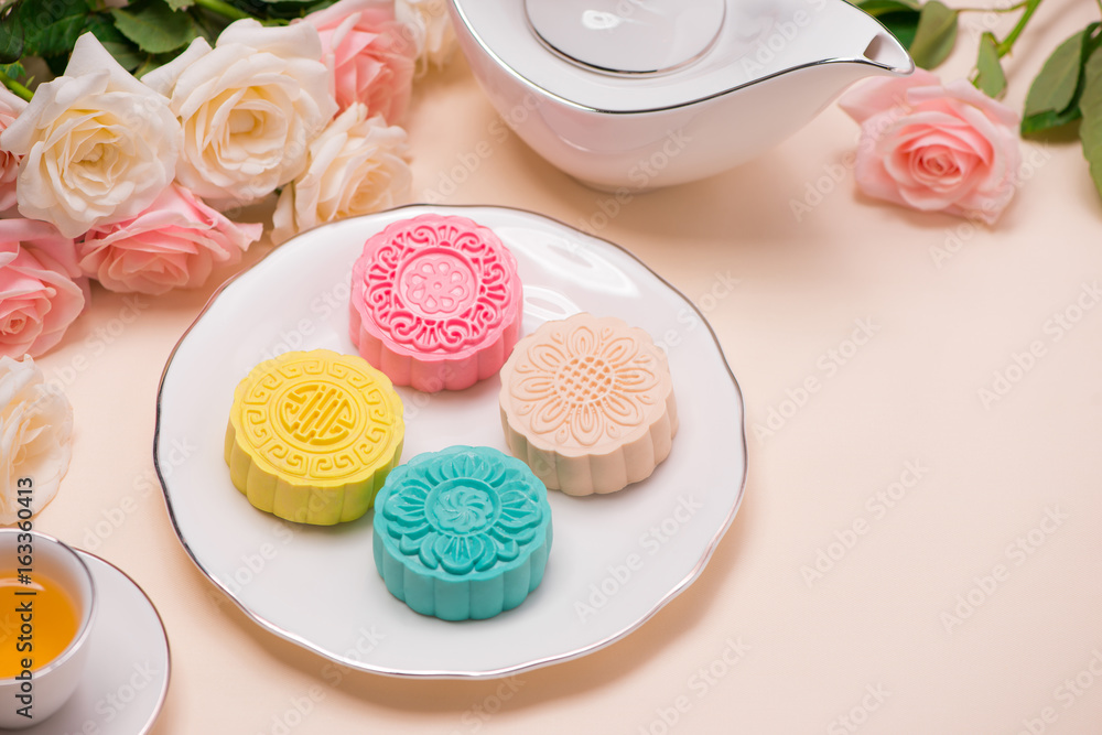 Sweet color of snow skin mooncake. Traditional mid autumn festival foods with tea on table setting.