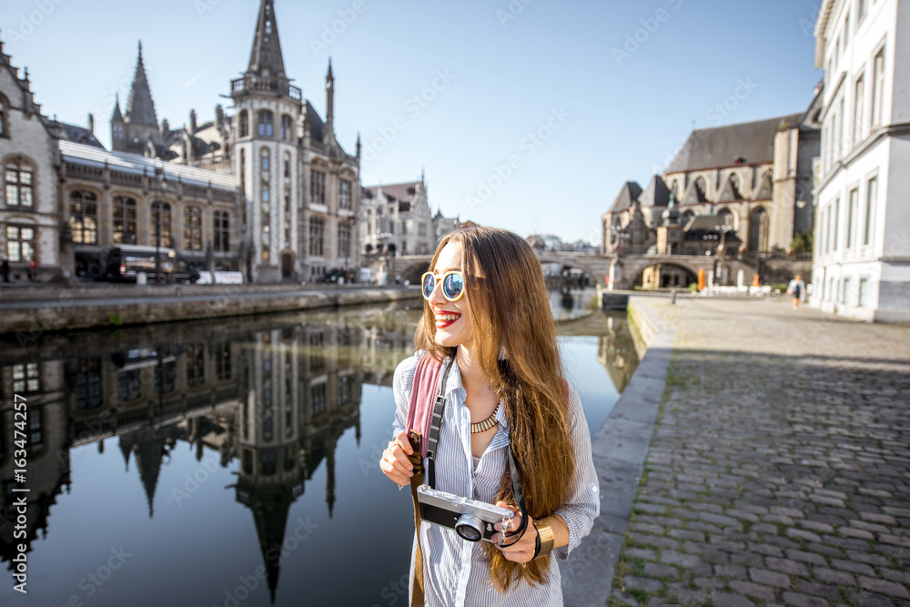 年轻的女游客带着相机在水道附近散步，可以欣赏到老城区的美景