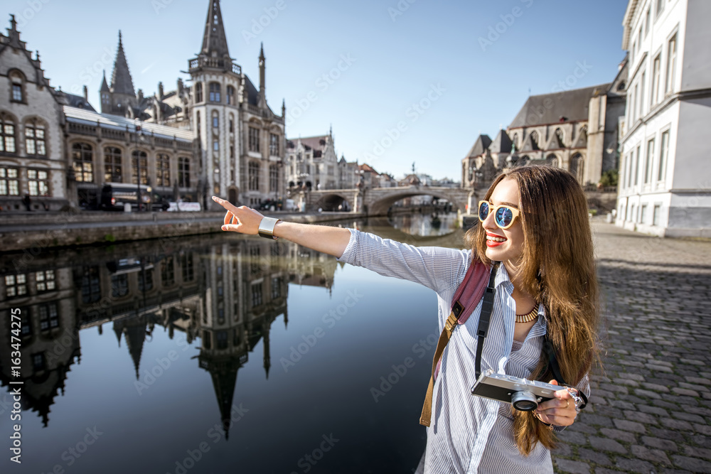 年轻的女游客带着相机在水道附近散步，可以欣赏到老城区的美景