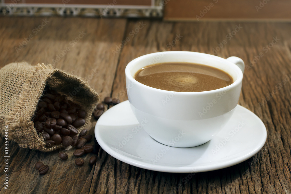 Coffee cup with coffee beans in sag wooden table