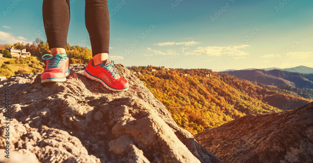 Woman standing at the edge of a cliff high above the mountains