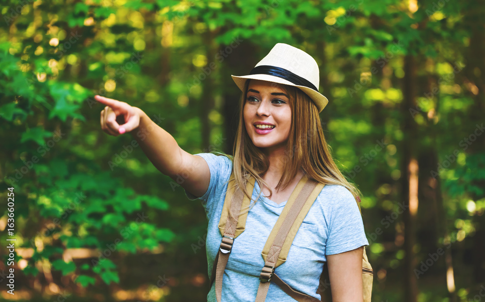 Young woman in the forest with a backpack and hat