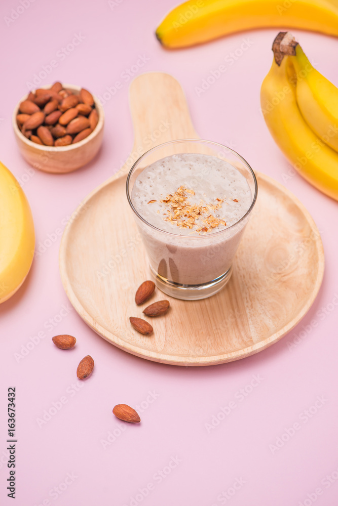 Fresh made banana smoothie in a glass on pink background