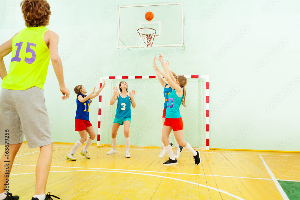 Teenage team playing basketball in gym