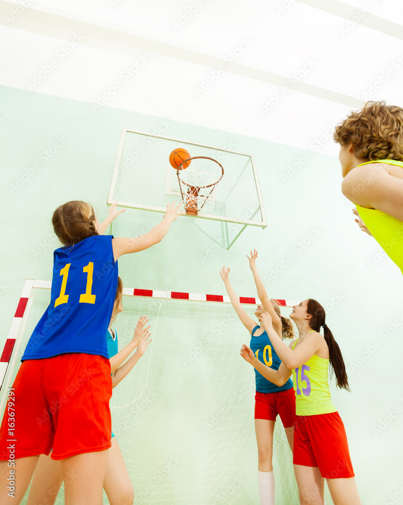 Teenagers playing basketball in sports hall