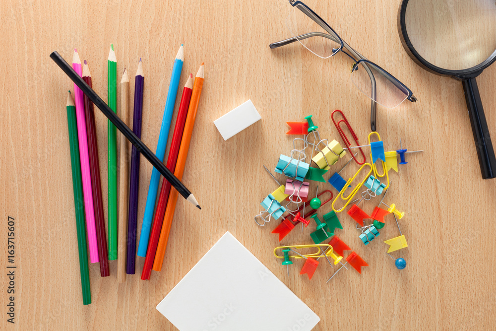 business objects of colorful pencils,white paper note,Magnifying glass,clips and glasses on wooden o