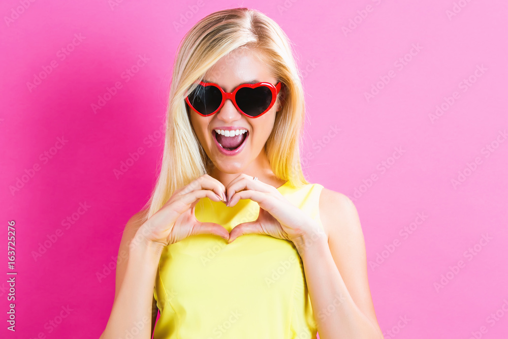 Young woman with sunglasses on a pink background