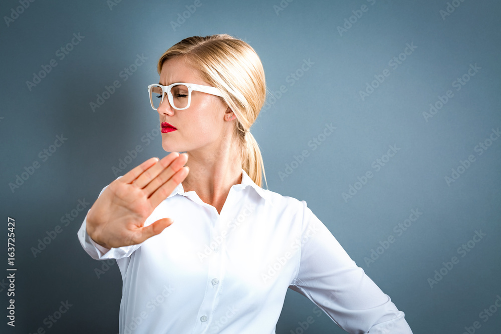 Young woman making a rejection pose on a gray background