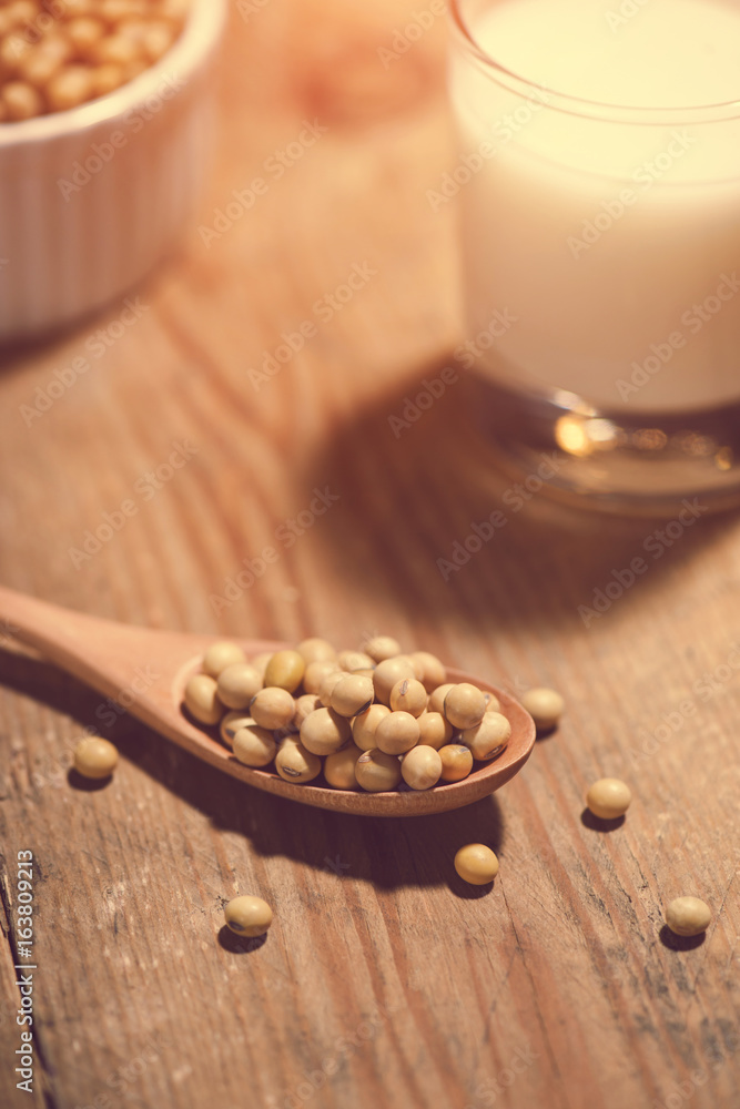 Soy milk or soya milk and soy beans in spoon on wooden table.