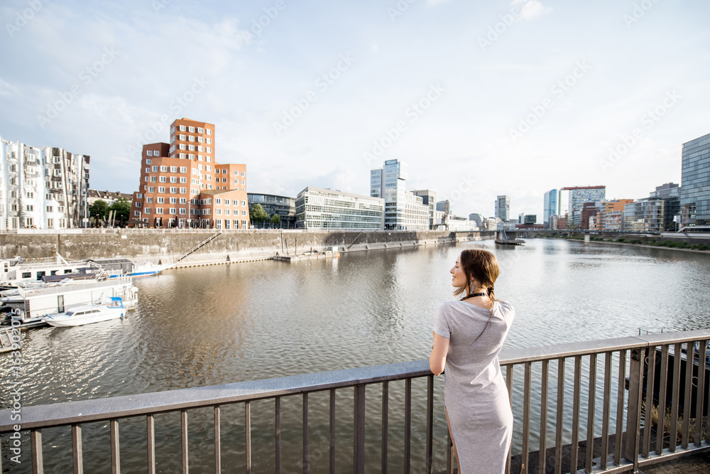 德国杜塞尔多夫市，一位年轻女子在港口欣赏现代建筑的美景