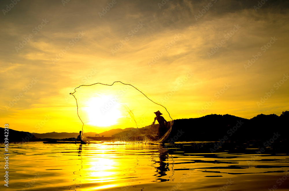 People fishing in river On the bright sky a beautiful golden color in Thailand.