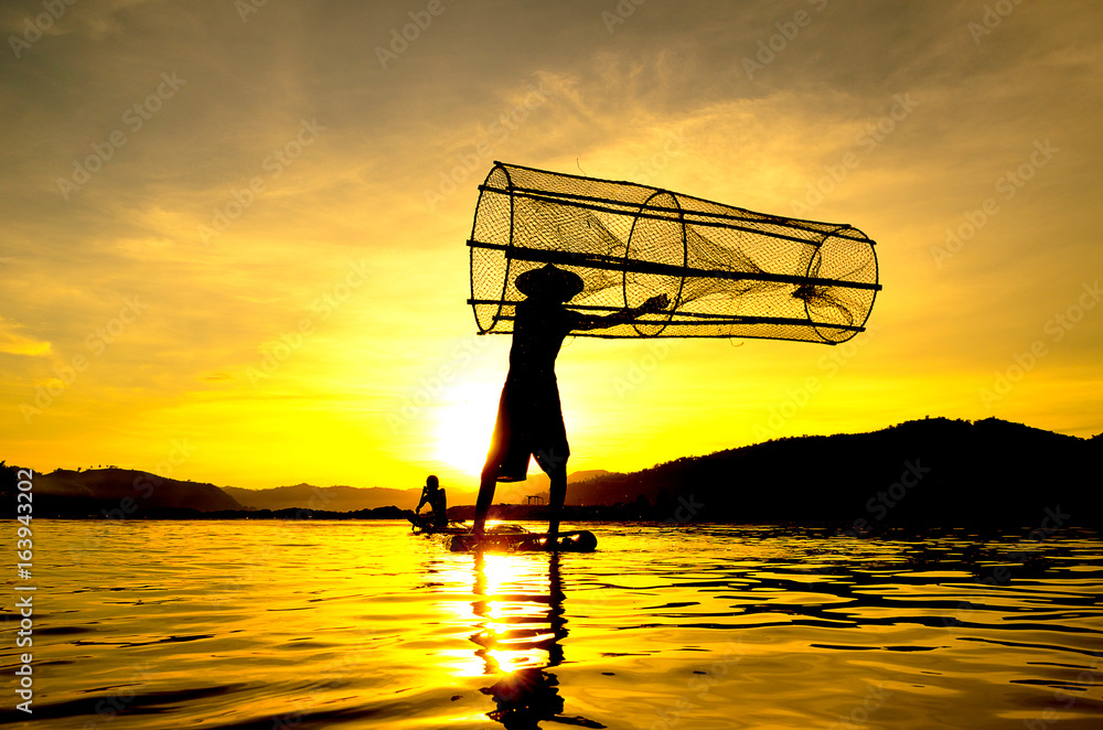 People fishing in river On the bright sky a beautiful golden color in Thailand.