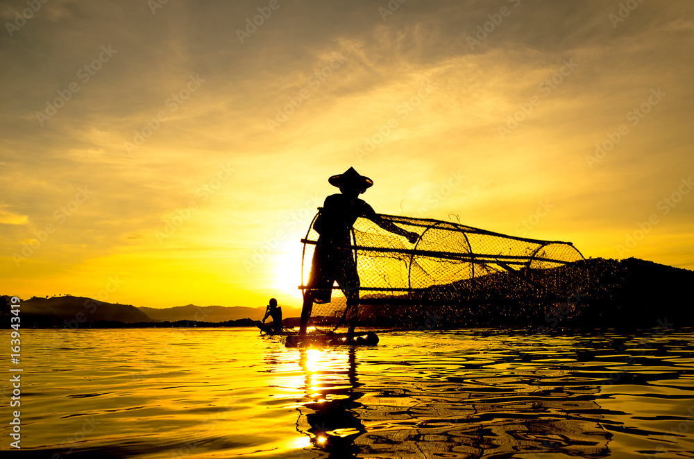 People fishing in river On the bright sky a beautiful golden color in Thailand.