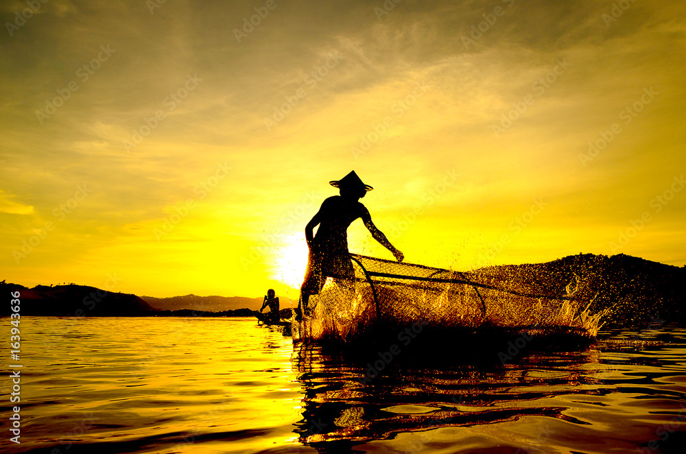 People fishing in river On the bright sky a beautiful golden color in Thailand.