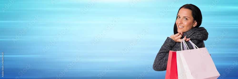 Shopper over shoulder with bags against blurry blue background