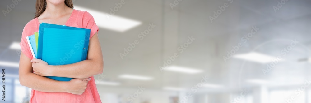 Student holding files and folders with blurred background