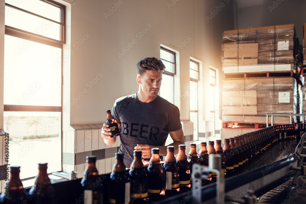 Businessman testing the beer bottle at brewery