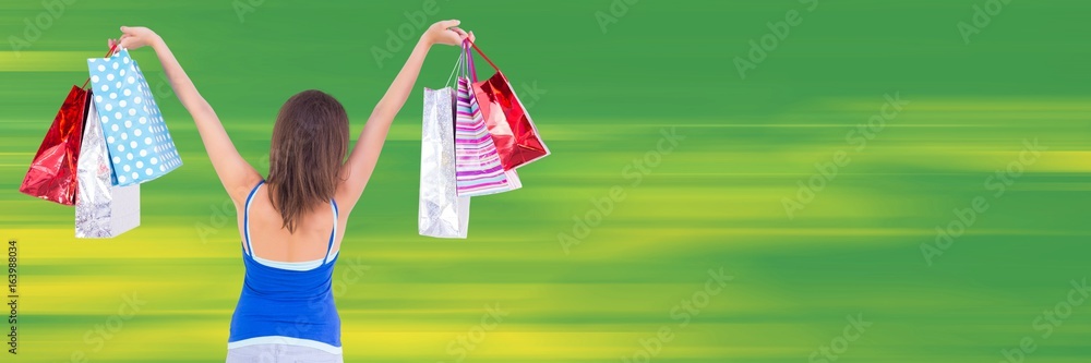 Back of shopper with bags in air against blurry green background