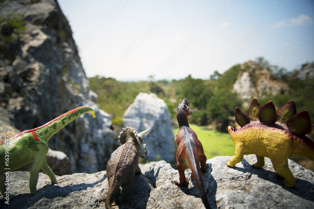 Diverse Group of Dinosaur Toys Standing on the Rock Together