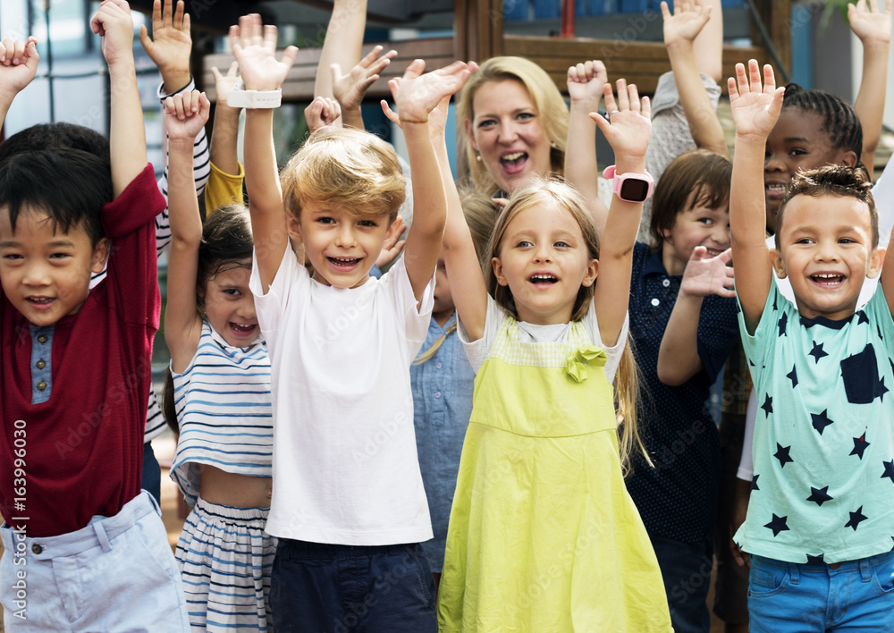 Group of diverse kindergarten students with arms raised