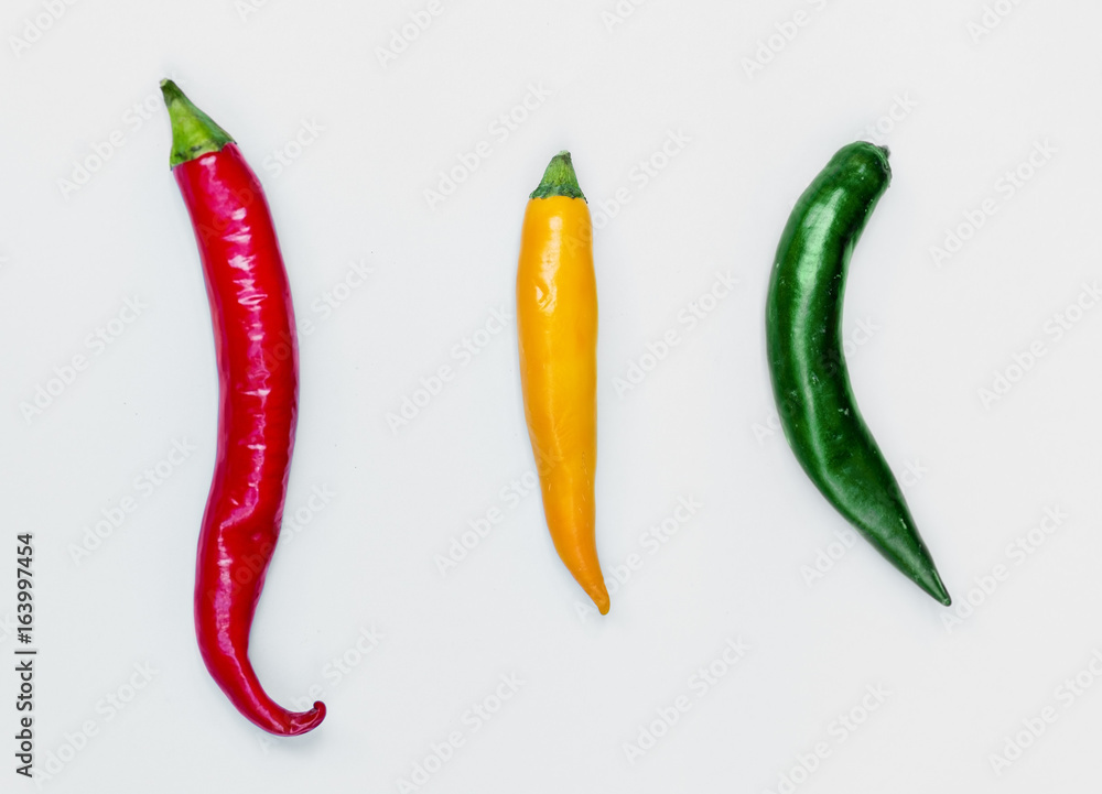 Aerial view of fresh red green yellow chili peppers on white background