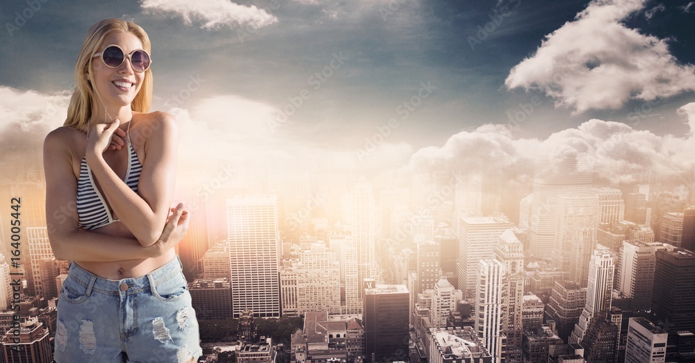 Woman in bikini and shorts against skyline with clouds