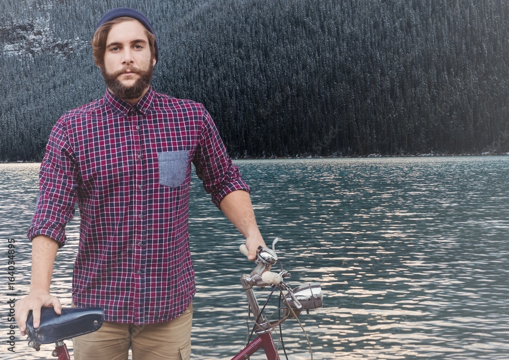 Millennial man with bicycle against river and forest