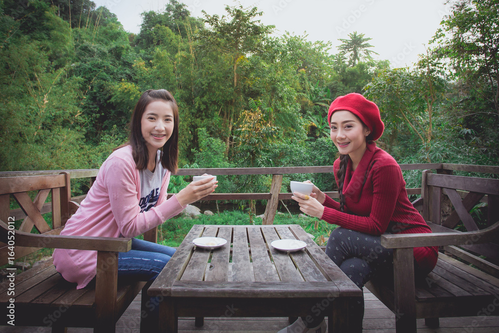 Asian girl and her friend drink coffee a refreshing natural ambiance.