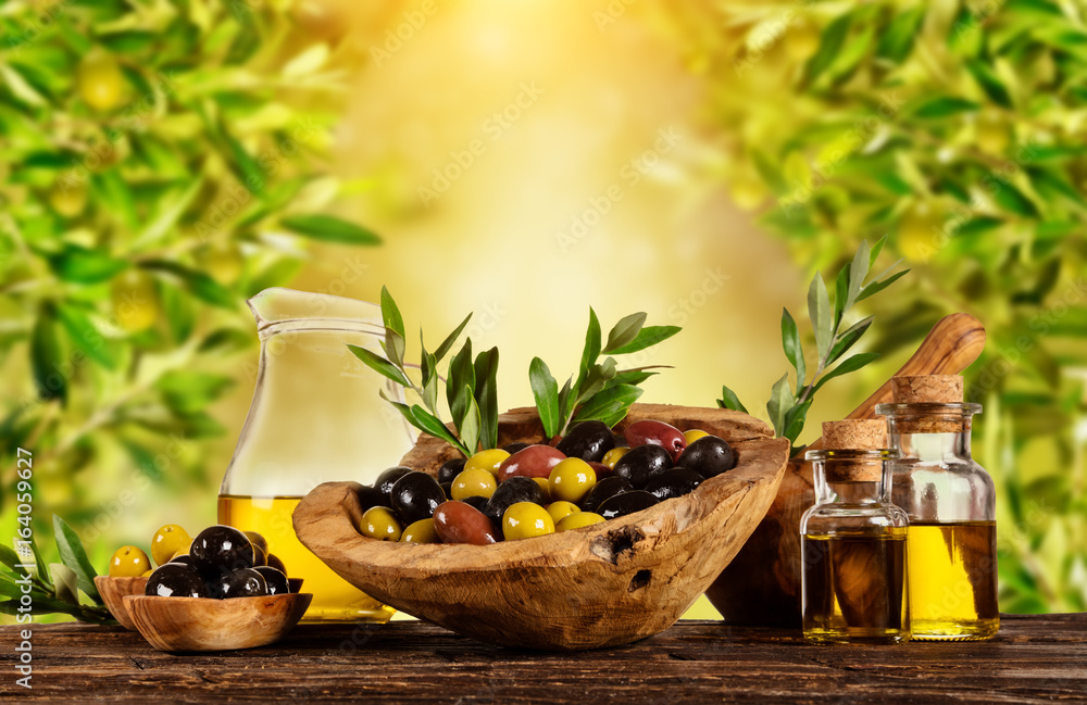 Freshly harvested olives berries in wood bowls and pressed oil