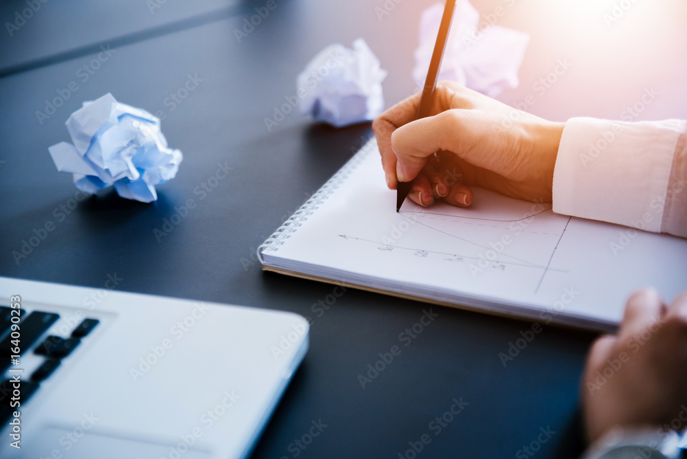 Close up of female hands with notebook, pencil and cramped paper wads on table.