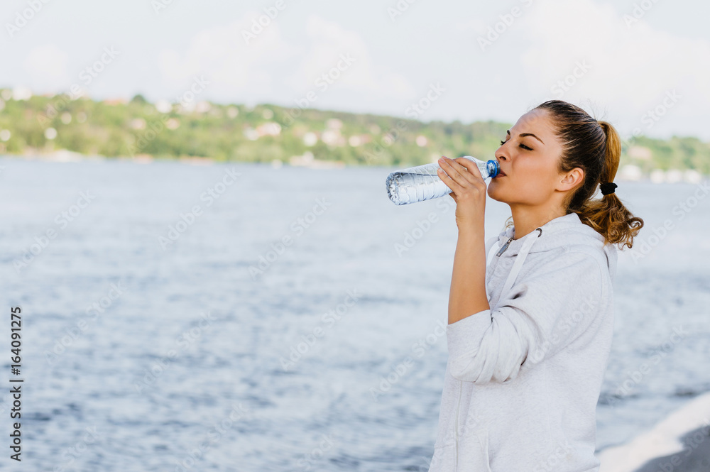 美丽的女人在锻炼后喝水。