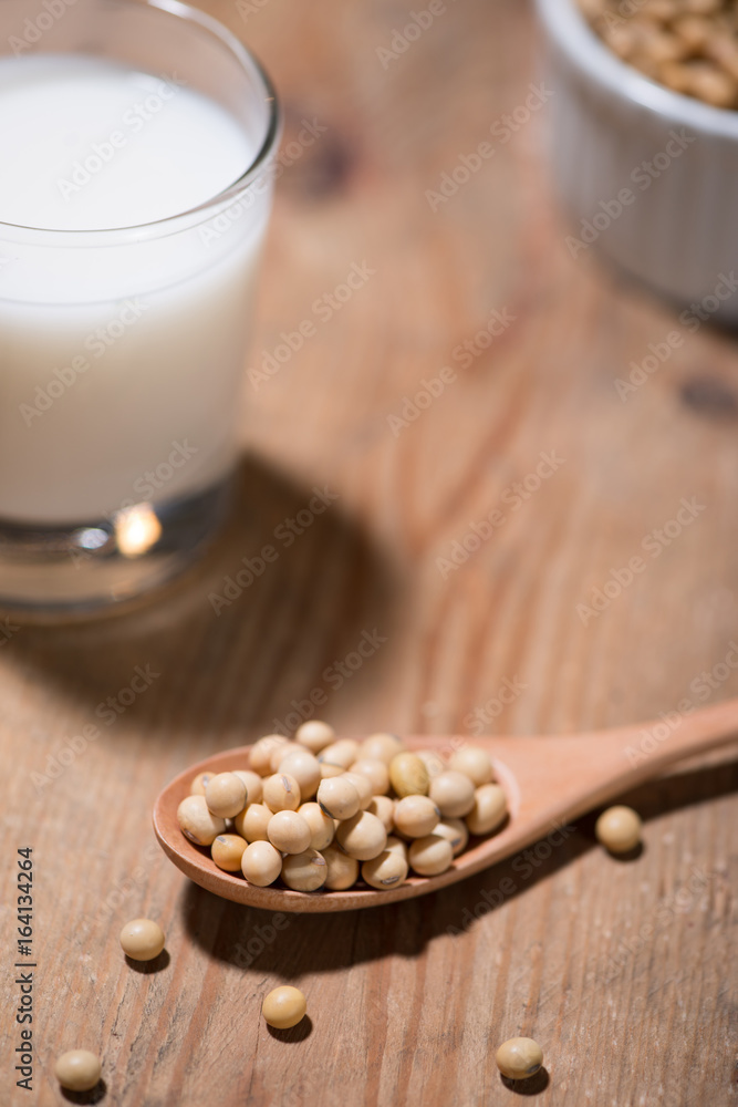 Soy milk or soya milk and soy beans in spoon on wooden table.