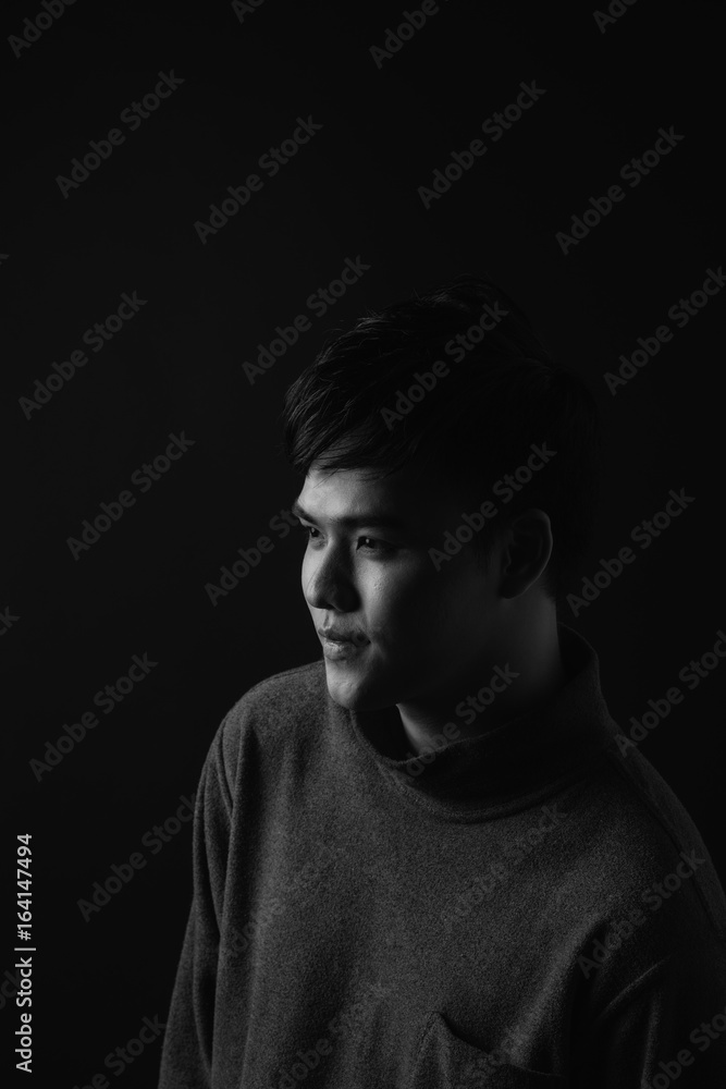 Young asian mans portrait against black background