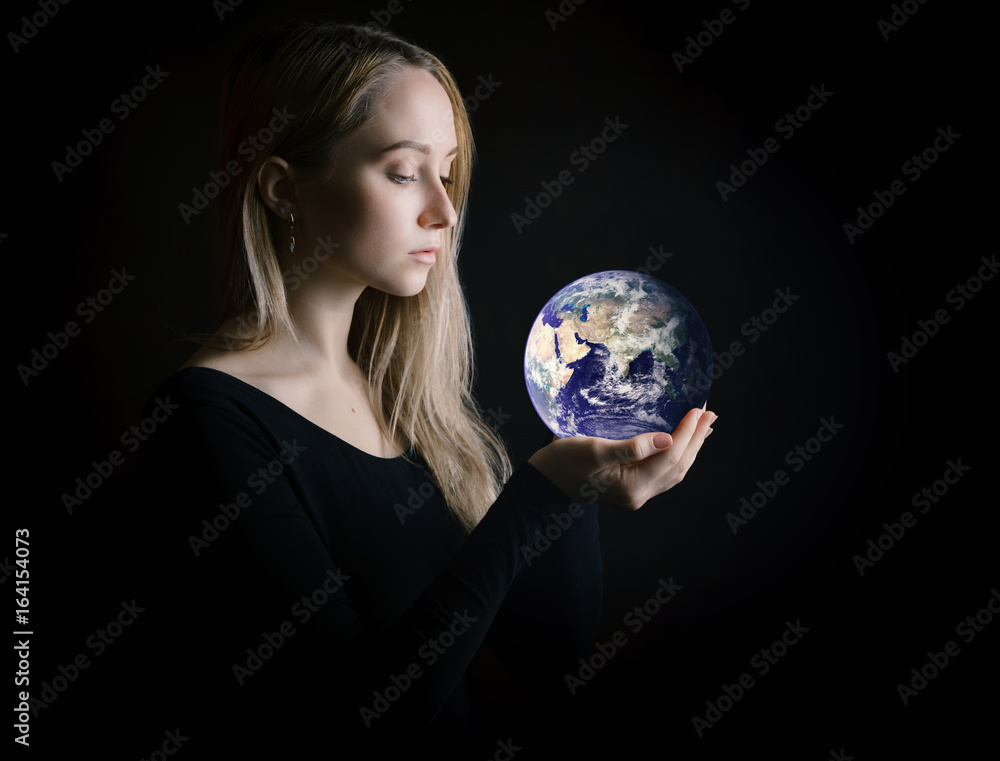 Young woman holding Earth in her arms. Elements of this image furnished by NASA.