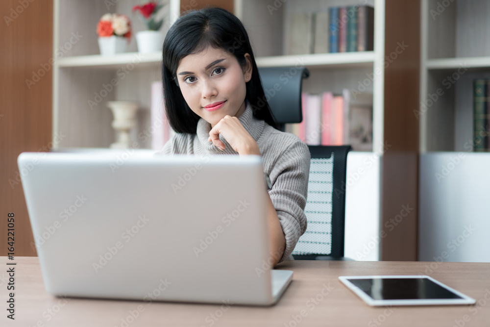 Asian young smart woman manager with casual doing her business work with laptop and sitting on chair