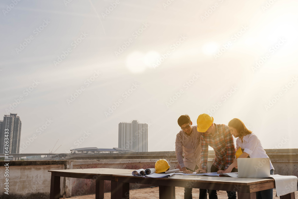 three construction engineers working outdoors in construction site with copy space