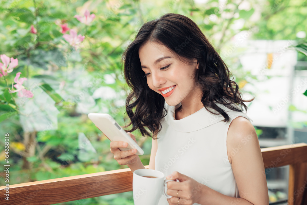 自信的年轻亚洲女性，穿着智能休闲服，用智能手机打字。